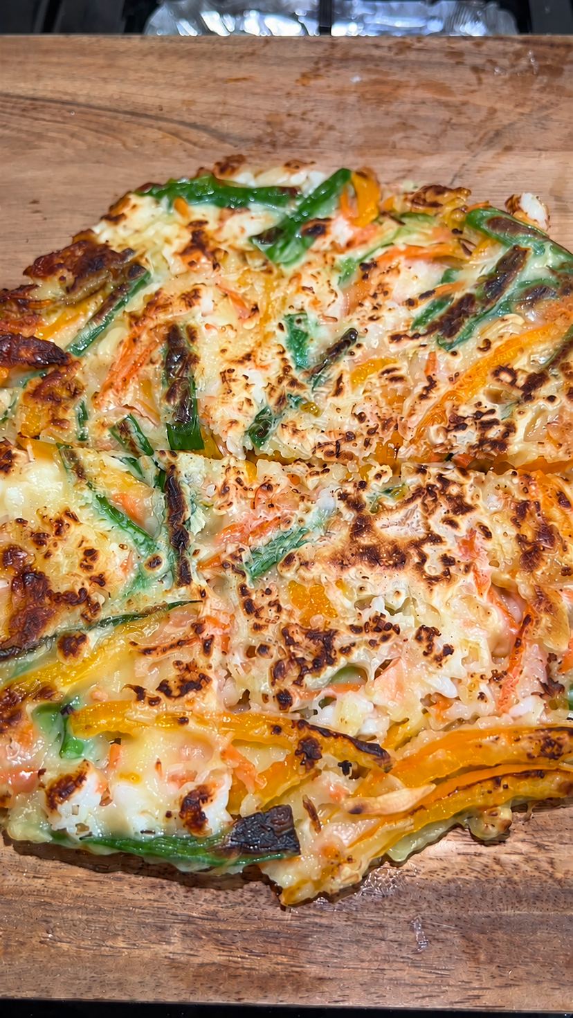 Golden brown crispy Korean seafood pancake cut into wedges with visible shrimp and green onion pieces.